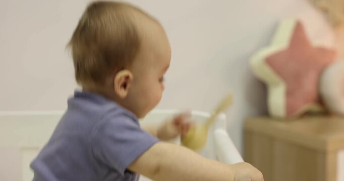 Cute little baby with wooden rattle in crib at home. Camera moving forward