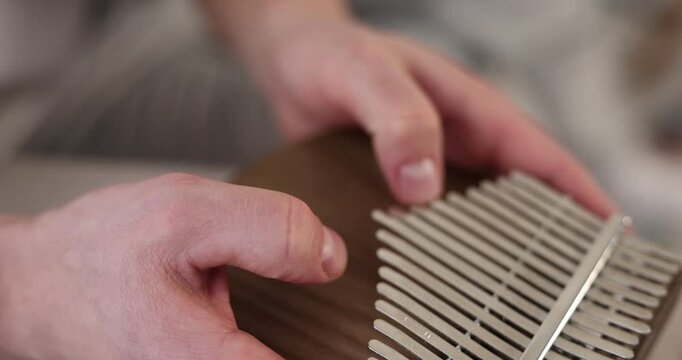 Man playing kalimba indoors, closeup. Musical instrument