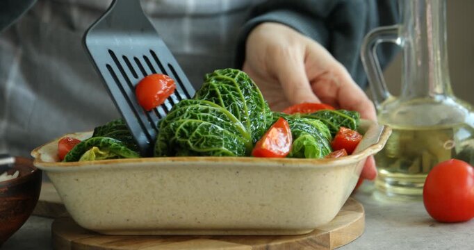 Woman with stuffed cabbage rolls at grey table, closeup