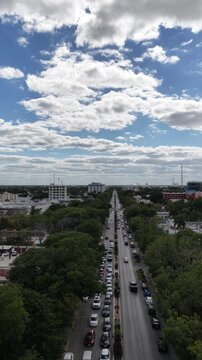 
Aerial drone flying forward over Paseo Montejo with heavy traffic and cloudy blue sky in M&eacute;rida, Yucat&aacute;n, M&eacute;xico. Vertical video