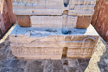 Ancient marble stele with intricate carvings and reliefs in historic setting