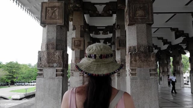 A woman walks among the columns of the Sri Lanka Independence Monument.