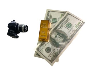 Camera, gold bar, and stack of U.S. dollar bills arranged together for financial concept imagery © MR HEPPY