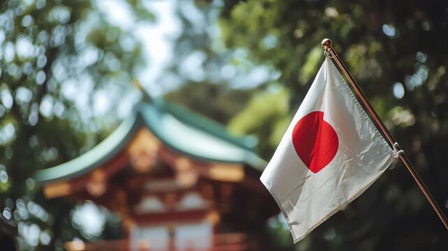 A Japanese flag waves gently in front of a traditional temple building, set against a backdrop of lush green trees.