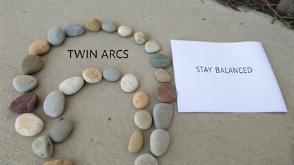 Twin Arcs of Smooth River Stones Demonstrating Balance and Harmony on a Neutral Background with Inspiration Note
