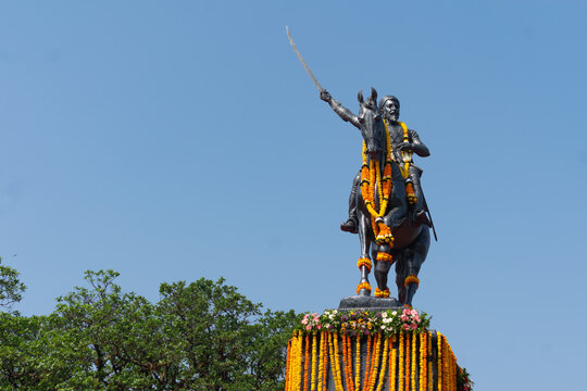 Equestrian statue of Chhatrapati Shivaji Maharaj adorned with vibrant flower garlands, symbolizing Maratha heritage, forts like Raigad, Pratapgad and Torna, and promoting Maharashtra tourism, history
