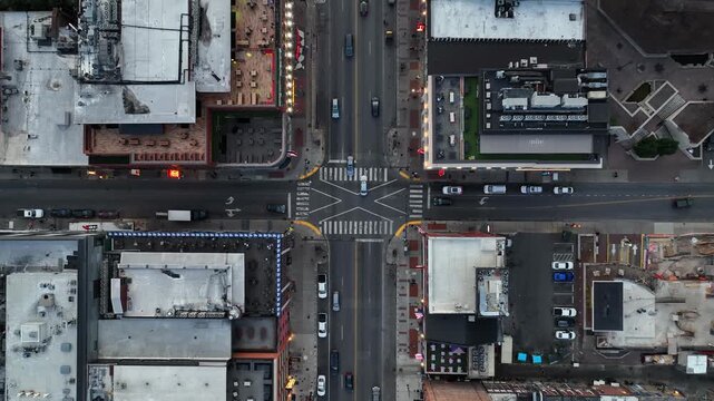 American downtown intersection with cars, crosswalks and surrounding buildings. Urban layout, traffic flow and city infrastructure from above. Aerial top down flyover.