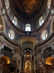 Fototapeta premium The dark, moody golden interior of St. Peter’s Church (Peterskirche), a stunning Baroque landmark located in Vienna’s historic city centre, featuring ornate decorations, and detailed frescoes.