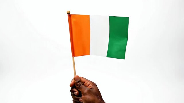 Hand holding Ivory Coast flag waving on white background