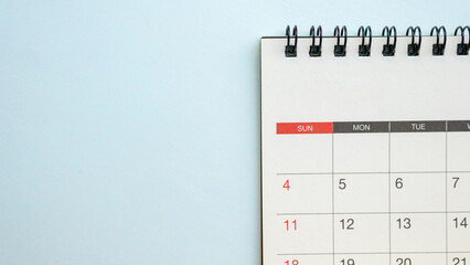Top view of blank spiral desk calendar on light blue background with ample copy space for scheduling