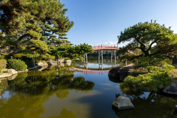 Obraz premium Japanese Ornamental Garden with lake and a red bridge.