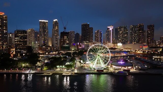 Miami downtown skyline at dusk with illuminated ferris wheel and waterfront marina, Florida, USA. g.