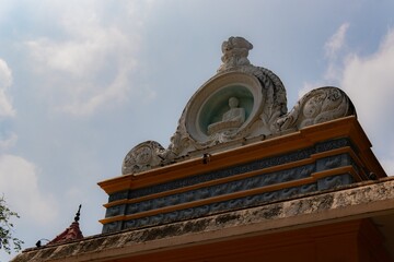 Ornate temple rooftop with intricate stone carvings under a partly cloudy sky.