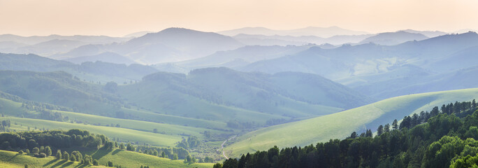 Ridge gradients in haze, panoramic view of the summer evening, hills and mountain slopes in sunset light