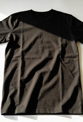 A black t-shirt lies crumpled on a white surface