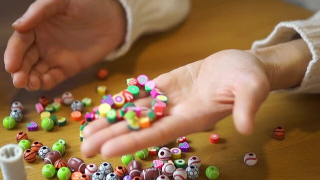 A woman takes off a bright, multi-colored fruit bead bracelet and holds it in her palms to display the finished handmade product.