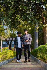 Obraz premium two indian teenagers boys looking smartphone and discussing at garden