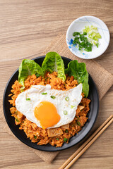 Top view of Korean kimchi fried rice with fried egg and spring onion on wooden background