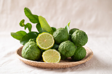 Kaffir lime fruit with leaf in basket on white fabric background, Thai food ingredient