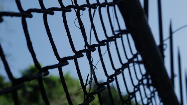 Chain Link Security Fence with Sharp Metal Spikes Against Clear Blue Sky