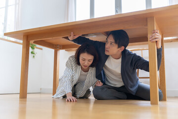 地震でテーブルに隠れる夫婦 © naka