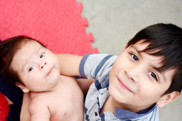 Latin boy holding his baby brother.
