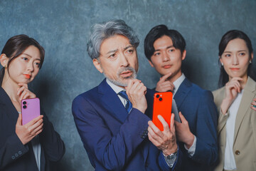 スマートフォンを手に持って悩むビジネスマン