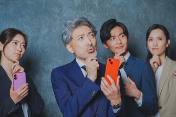 スマートフォンを手に持って悩むビジネスマン