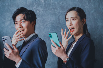 スマートフォンを手に持って驚くビジネスマン