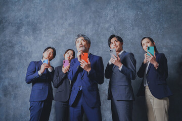 スマートフォンを手に持って悩むビジネスマン