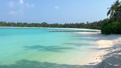 Crystal clear turquoise lagoon and white sand beach in tropical Maldives paradise