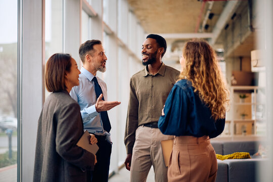 Happy diverse entrepreneurs communicating while working in office.