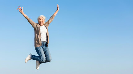 Happy Active Senior Woman Jumping Against Blue Sky