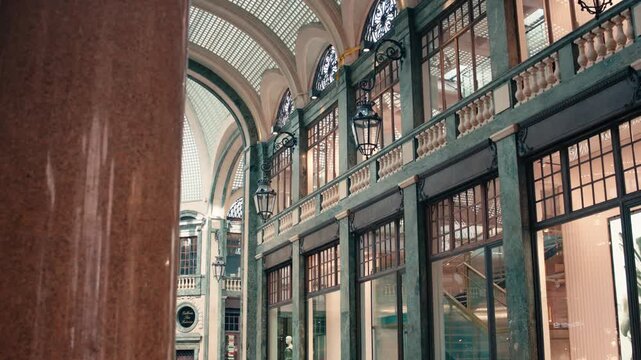 Low angle interior shot of Galleria Subalpina in Turin displaying ornate green columns, large windows, and classic architectural details of the historic covered shopping passage.
