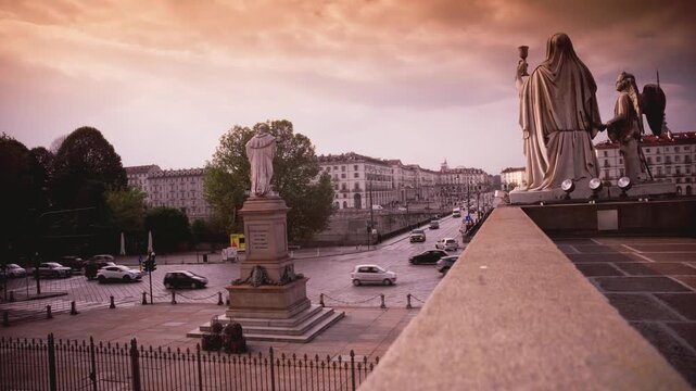 Atmospheric view from Gran Madre di Dio steps overlooking Po River and Piazza Vittorio Veneto in Turin. Features historic statues, bridge traffic, and dramatic evening sky in Italy.