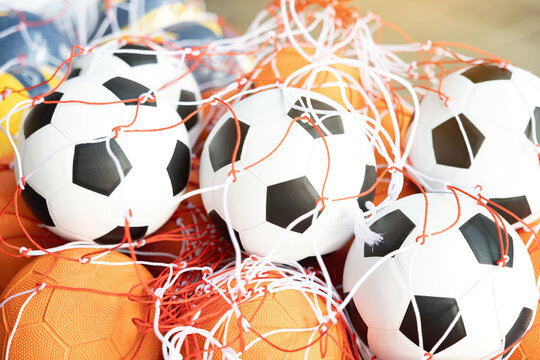 Group of classic soccer balls and basketballs in red nylon net bags for sports training.