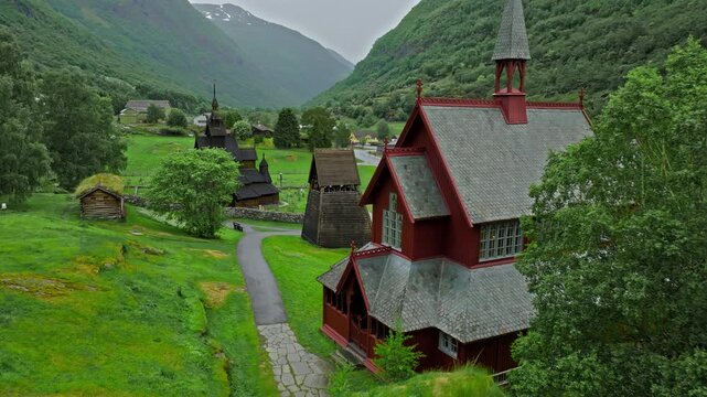 Drone view of red historic buildings Borgund Stave Church, Norway. Close up view of traditional architecture stands in a peaceful rural mountain landscape.