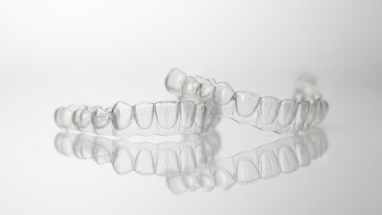Clear aligners for teeth straightening and smile correction on a white surface with reflection