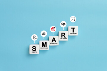 Smart goal for business strategy concept. specific, measurable, achievable, relevant and time-bound text on dice or cubes with icons on blue background