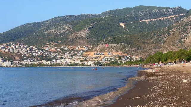 Long sandy beach in sunny weather, located in the center of Finike. Beach on the Mediterranean coast and the coastal city of Finike in Turkey on a sunny summer day. 4K