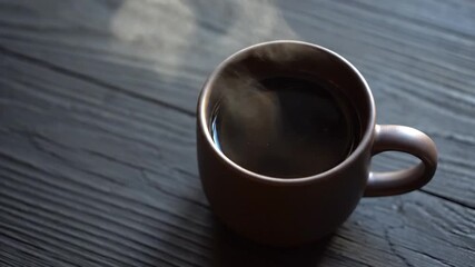 A steaming cup of coffee placed on a rustic wooden table, with soft steam rising, creating a cozy atmosphere perfect for relaxation or morning routines