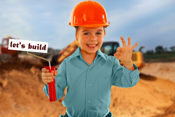 A young boy is wearing a hard hat and holding a paintbrush