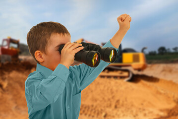 A young boy is looking through binoculars at a construction site