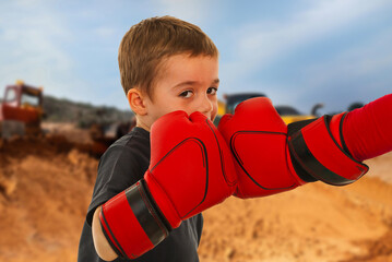 A boy wearing red boxing gloves is about to punch another boy