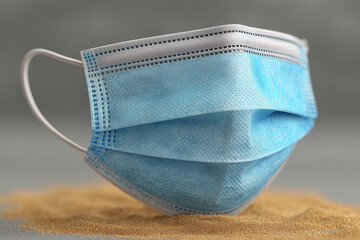 Stacked blue surgical masks on sand background