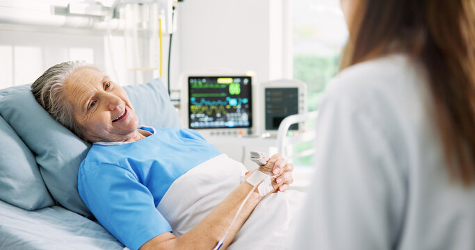 Senior woman, doctor and discussion in hospital bed, rest and happy for recovery, good news or wellness. Elderly person, medical worker and talk with smile, report and support for healing at clinic