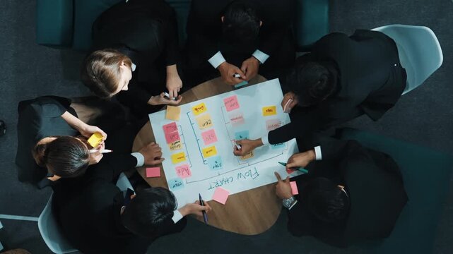 Top down view of business people hands making scrum task board to manage workflow in workplace. Diverse marketing team drawing a line and use colorful stick notes to work on kanban. Directorate.