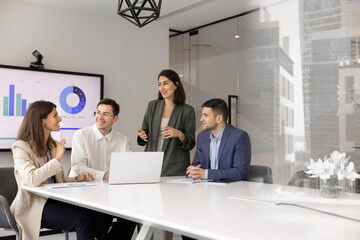 Professional business meeting in modern conference room. Four staff members take part in corporate training or briefing gather together in modern boardroom with laptop, exchanging ideas and solutions