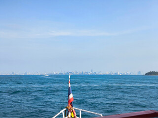 Obraz premium View from the bow of the boat to the sea and the city silhouette in the distance, traveling along the bay on a sunny day.