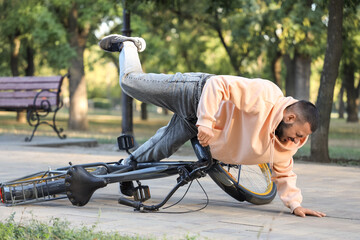 Young man falling off his bike in park